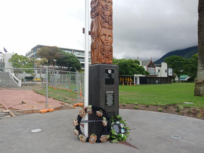The base of a pou whenua with wreaths