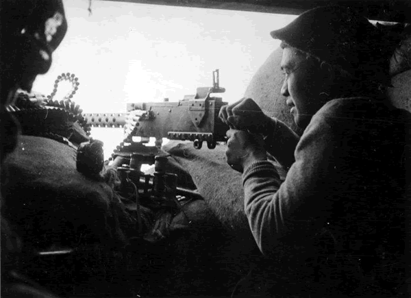 Firing a machine gun at the Senio River, Italy