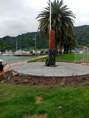 A pou whenua surrounded by a circle of concrete and new gardens
