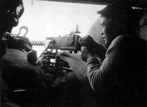Firing a machine gun at the Senio River, Italy